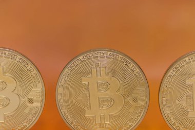 Turuncu arka plan makro görünümlü üç bitcoin ön görünümü