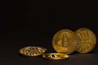 Önünde ve arkasında siyah arkaplan olan altın renkli değerli bitcoin 'ler