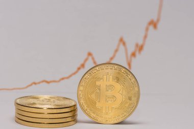 Borsa grafiği olan diğer bitcoin yığınının yanında tek bir bitcoin duruyor.