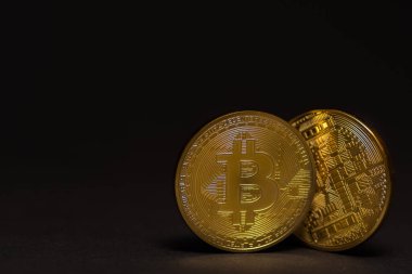 Önü ve arkası siyah detay görünümlü iki altın, parlak, değerli bitcoin.