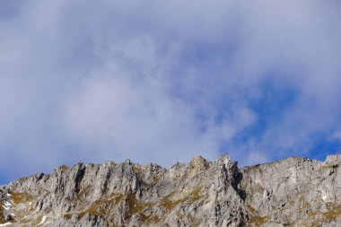 Yazın mavi gökyüzünde sivri dağlar ve yumuşak bulutlar.