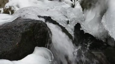 Kışın dağlarda kayalar ve buz ile berrak su