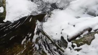 Kışın dağlarda kar ve buz arasındaki berrak su