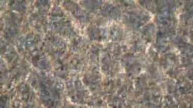 Yazın güneşin altında dalgalar ve taşlar.