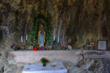 Mumları olan eski bir mağara çiçekler ve dağlarda resimleri olan dini heykeller.