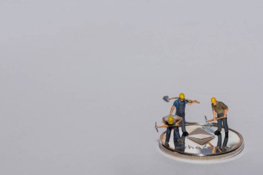 Tek bir gümüş eter kripto para biriminin üzerinde duran üç madenci. Sağ arka planı gri.