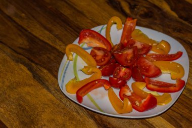 Ahşap bir masada kırmızı ve turuncu biber kesiği.