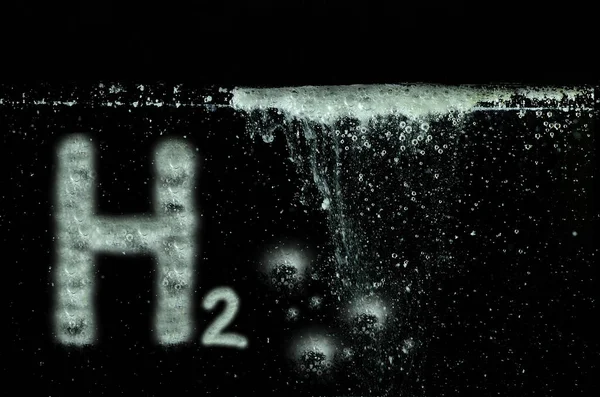 H2水素の手紙と黒い水の中の多くの小さな白い泡 — ストック写真