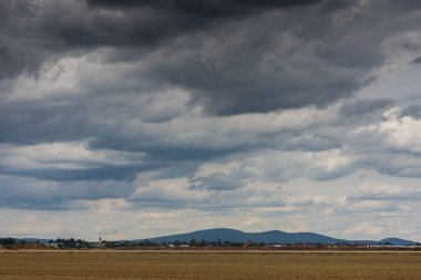 köy dağları, tarlalar ve bulutlarla kaplı düz bir arazi.