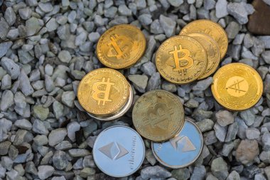 Birçok değerli altın ve gümüş sikke Bitcoin eter ve beyaz çakıl üzerinde yatan kripto para biriminden ada