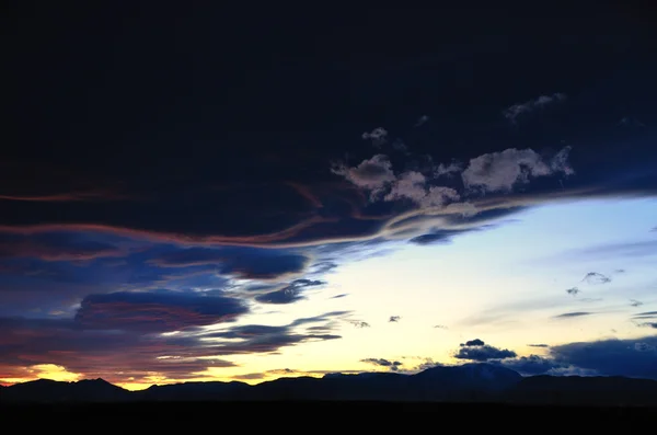 Puesta de sol con montañas y nubes negras — Foto de Stock