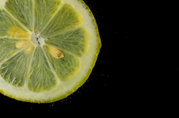 Limón en agua con burbujas y negro — Foto de Stock