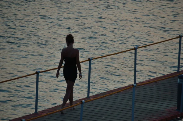 Mujer en la tarde en embarcadero y mar —  Fotos de Stock