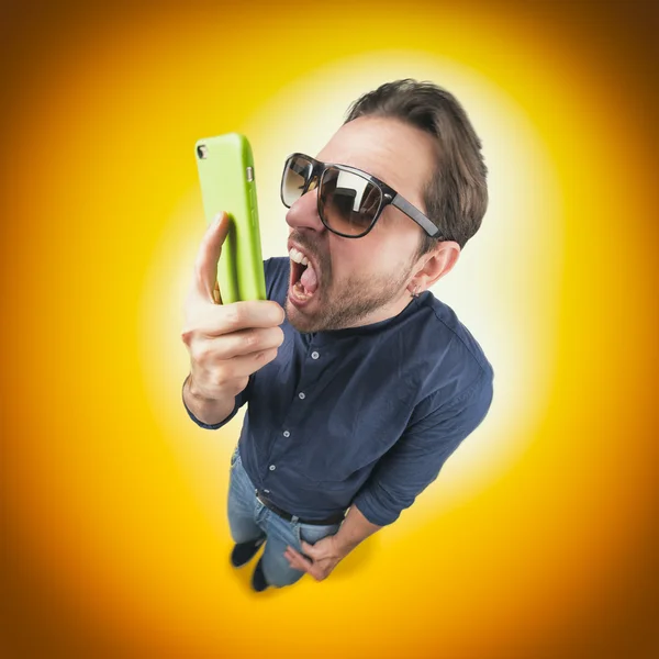 Komik kızgın genç adam cep telefonundan çığlık — Stok fotoğraf