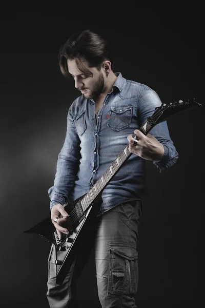 Handsome guitarist playing his electric guitar on black backgrou — Stock Photo, Image