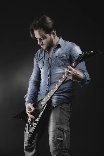 Beau guitariste jouant sa guitare électrique sur backgrou noir — Photo