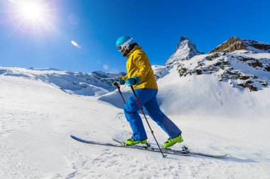 Arka planda Matterhorn, İsviçre Alplerinde Zermatt ile taze toz karda kayak yapan adam..