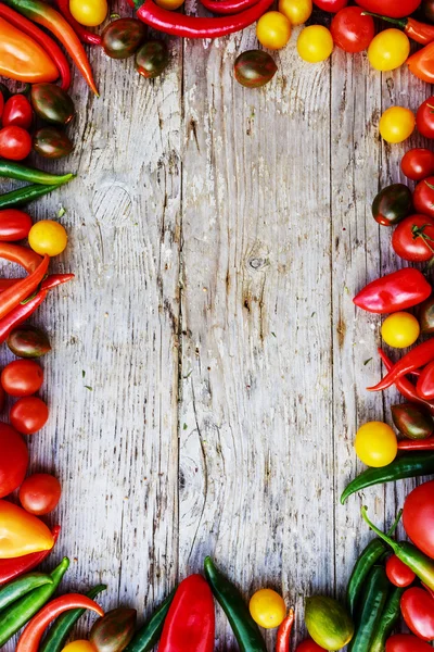 Frame of tomatoes and paprica family varieties over wooden background — Stock Photo, Image