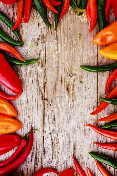 Frame of paprika family varieties over a rustic wooden background — Stock Photo, Image