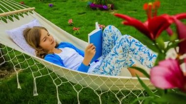Kız bahçede bir hamakta kitap okuma