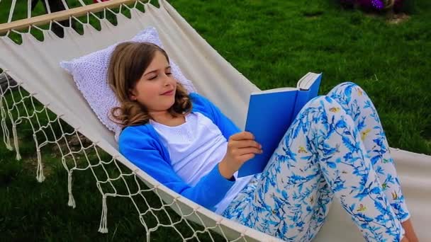 Dívka s knihou v houpací síti na zahradě — Stock video
