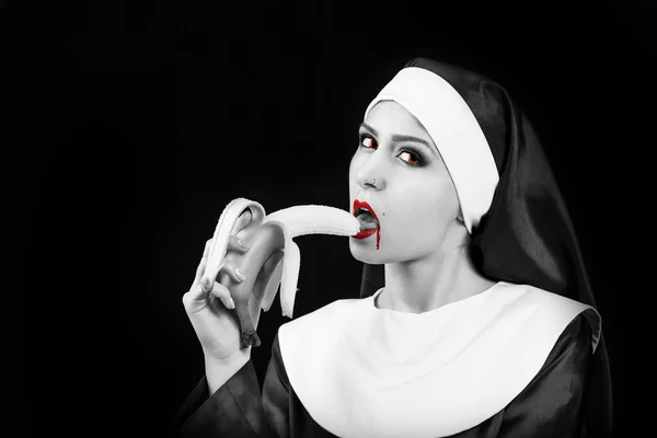 Vampire woman eating banana in nun suit — Stock Photo, Image