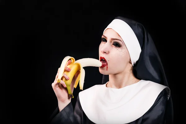 Vampiro donna mangiare banana in abito suora — Foto Stock