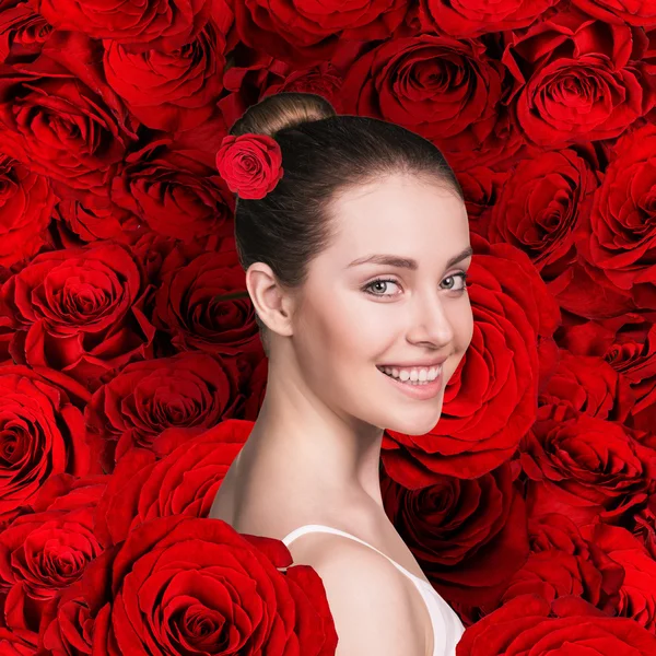 Женское лицо на фоне красных роз — стоковое фото