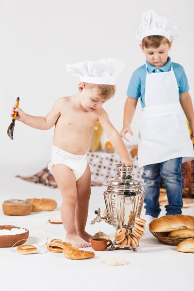 Liten flicka och rolig pojke bär kock hattar — Stockfoto