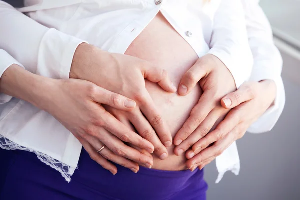 Mulher grávida com as mãos em forma de coração — Fotografia de Stock