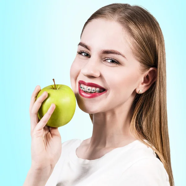 Молодая женщина с зубными скобками и зеленым яблоком — стоковое фото