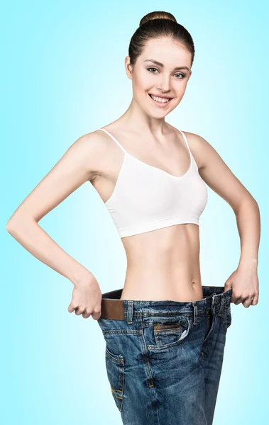 Schlanke Mädchen in großen Jeans zeigen Ergebnis — Stockfoto