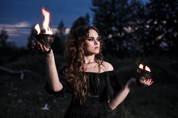 Portrait of dangerous woman witch with fire ball and dark make up