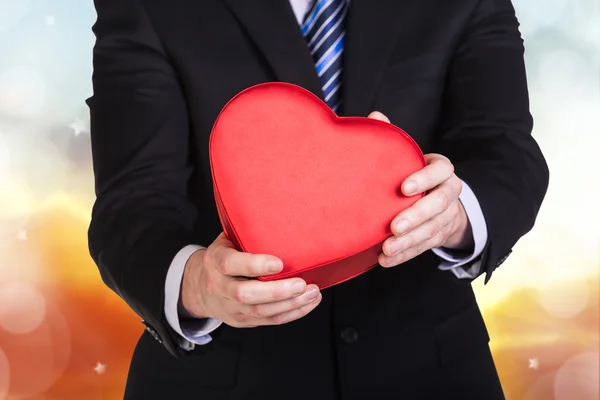 Junger Mann hält rote Herzkiste in der Hand — Stockfoto