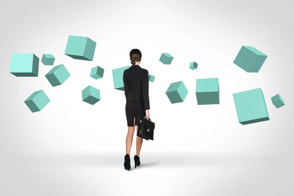 Business woman looking at turquoise cubes — Stock Photo, Image