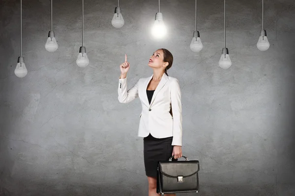 Business woman in room with hanging bulbs — Stock Photo, Image