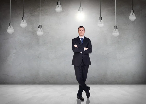 Businessman in the room with hanging bulbs — Stock Photo, Image