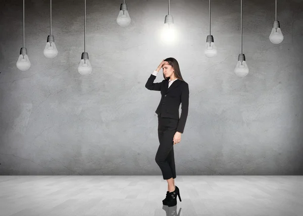 Business woman in room with hanging bulbs — Stock Photo, Image