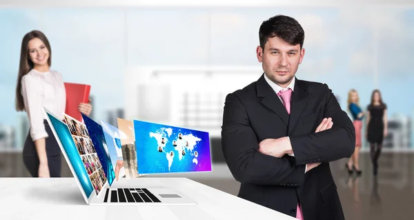 Businessman stands near laptop with many screens. — Stock Photo, Image