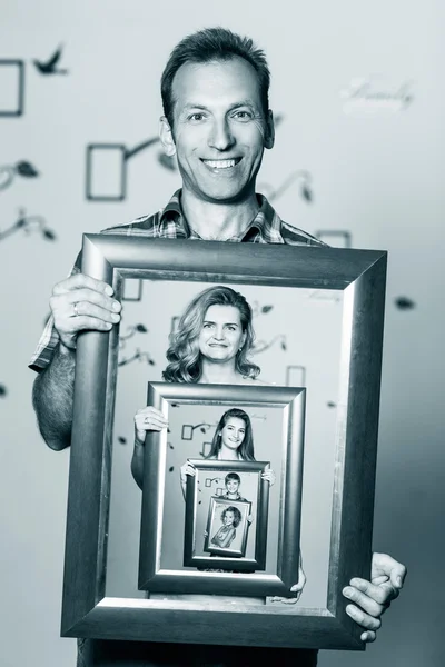 Happy father holding portrait with his family — Stock Photo, Image
