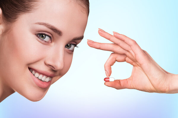 Young woman and drug capsules in hand