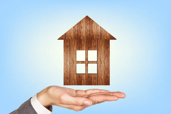 Wooden house in human hands — Stock Photo, Image