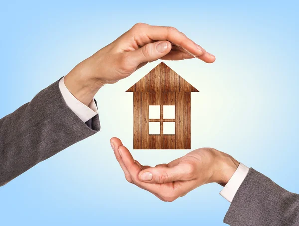 Wooden house in human hands — Stock Photo, Image