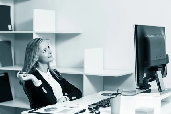 Kvinna sitter vid skrivbordet med dator — Stockfoto