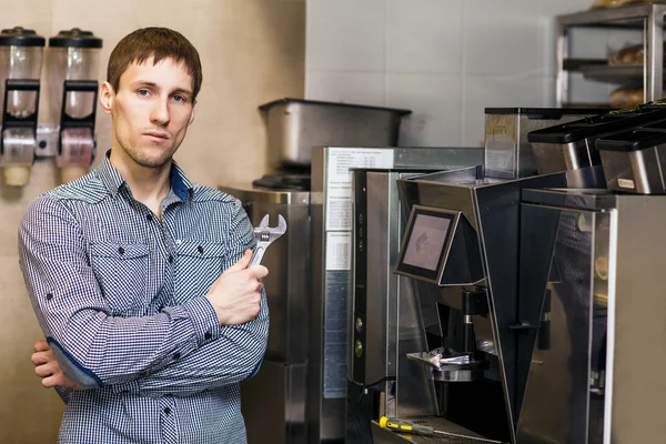 Barista de pé com chave perto de cafeteira — Fotografia de Stock