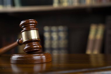Hukuk teması. Yargıç odası. Gavel kahverengi masada. Kitaplıkta yasal kitap koleksiyonu.