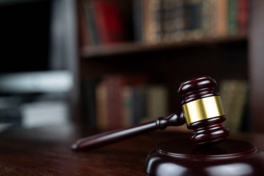 Hukuk teması. Yargıç odası. Gavel kahverengi masada. Kitaplıkta yasal kitap koleksiyonu.