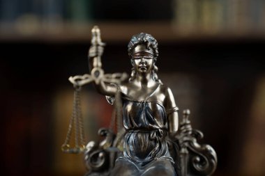 Hukuk ve adalet kavramı. Yargıç odası. Kahverengi masadaki heykel. Kitaplıkta yasal kitap koleksiyonu.