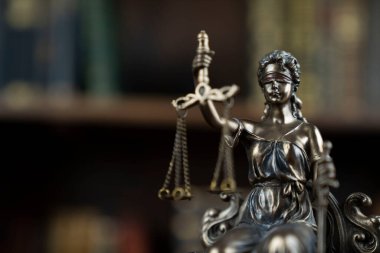 Hukuk ve adalet kavramı. Yargıç odası. Kahverengi masadaki heykel. Kitaplıkta yasal kitap koleksiyonu.