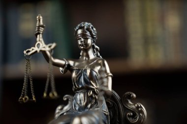 Hukuk ve adalet kavramı. Yargıç odası. Kahverengi masadaki heykel. Kitaplıkta yasal kitap koleksiyonu.